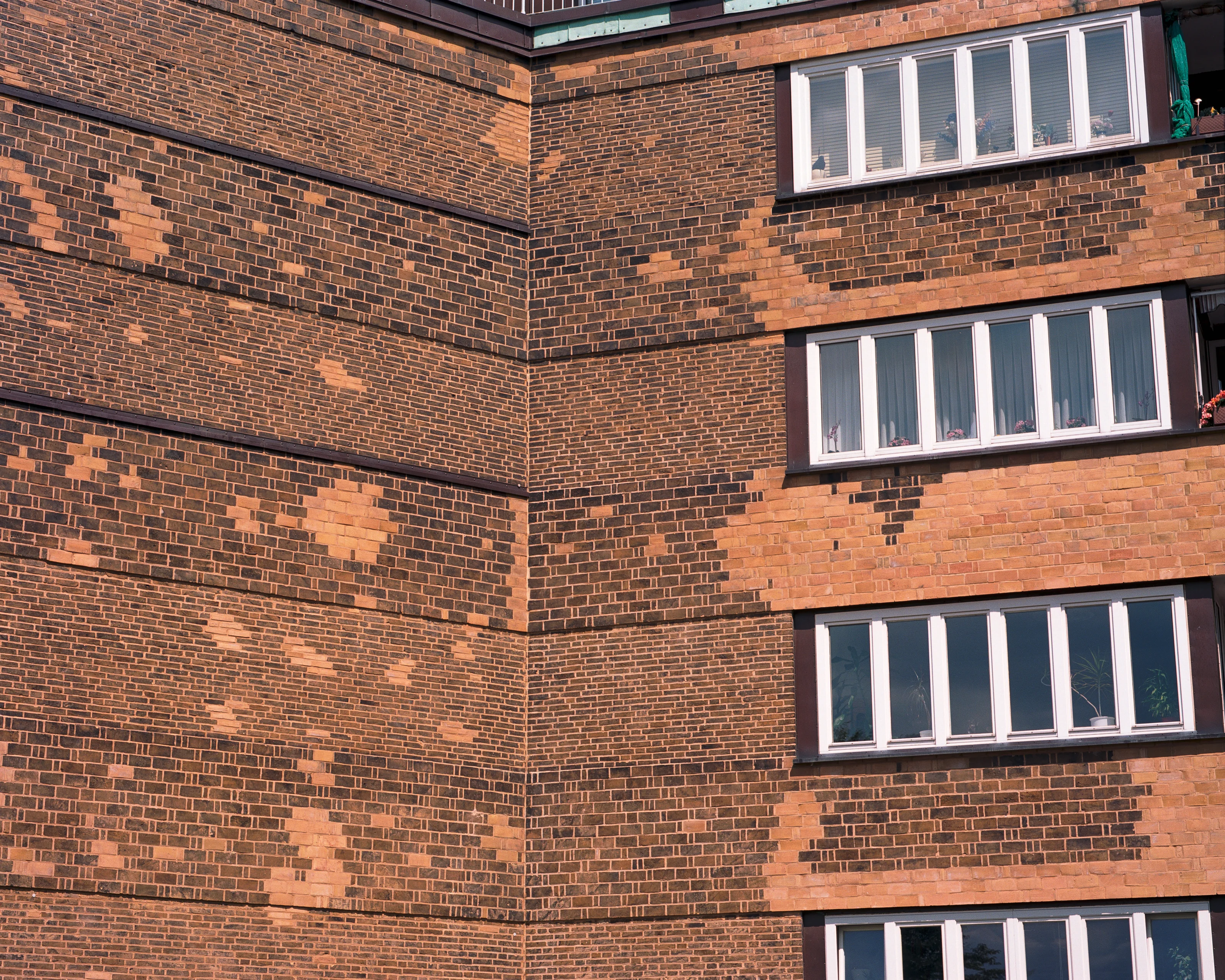 Brick building facade with large windows and irregular patterns.