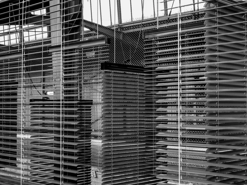 Close-up view of partially open window blinds casting shadows and patterns.