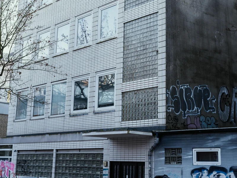 A multi-story building with tiled facade and graffiti on the lower level.