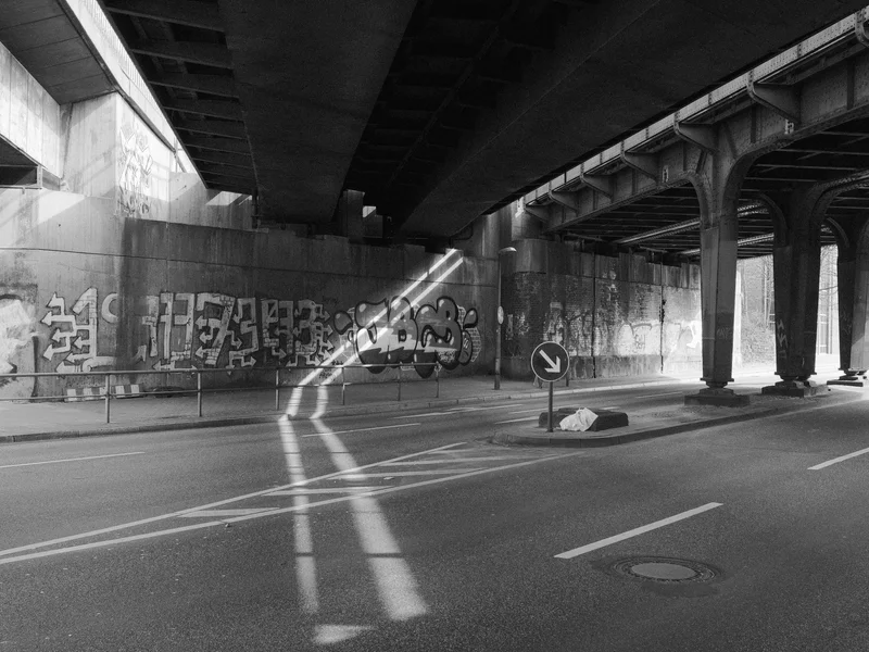 Underpass with graffiti on the walls and sunlight streaming through gaps.
