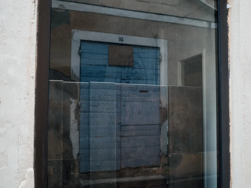 Reflection of a blue door in a building window.