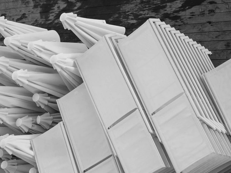 Folded white umbrellas stacked against a textured wooden deck.