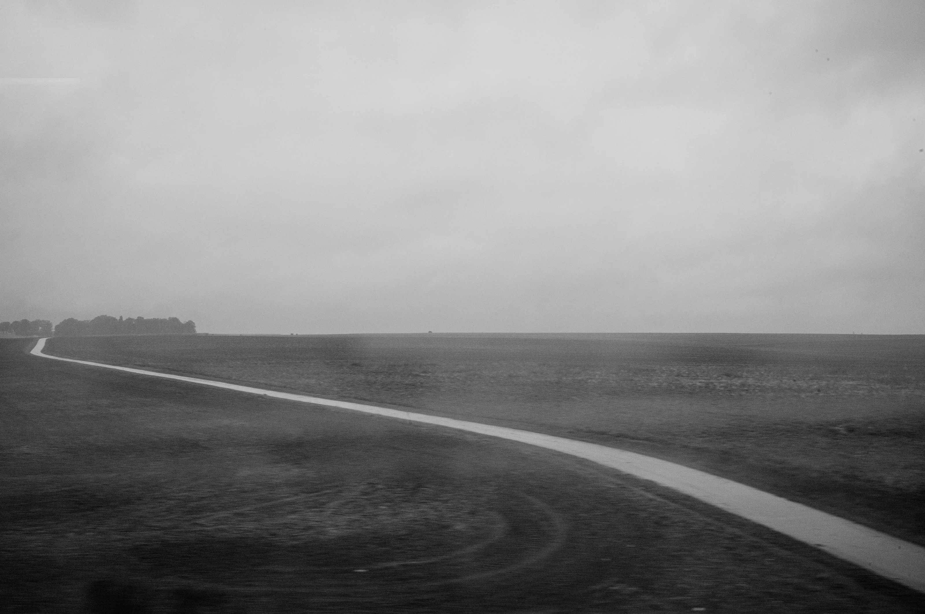 A winding path cuts through a vast, empty landscape under a cloudy sky.