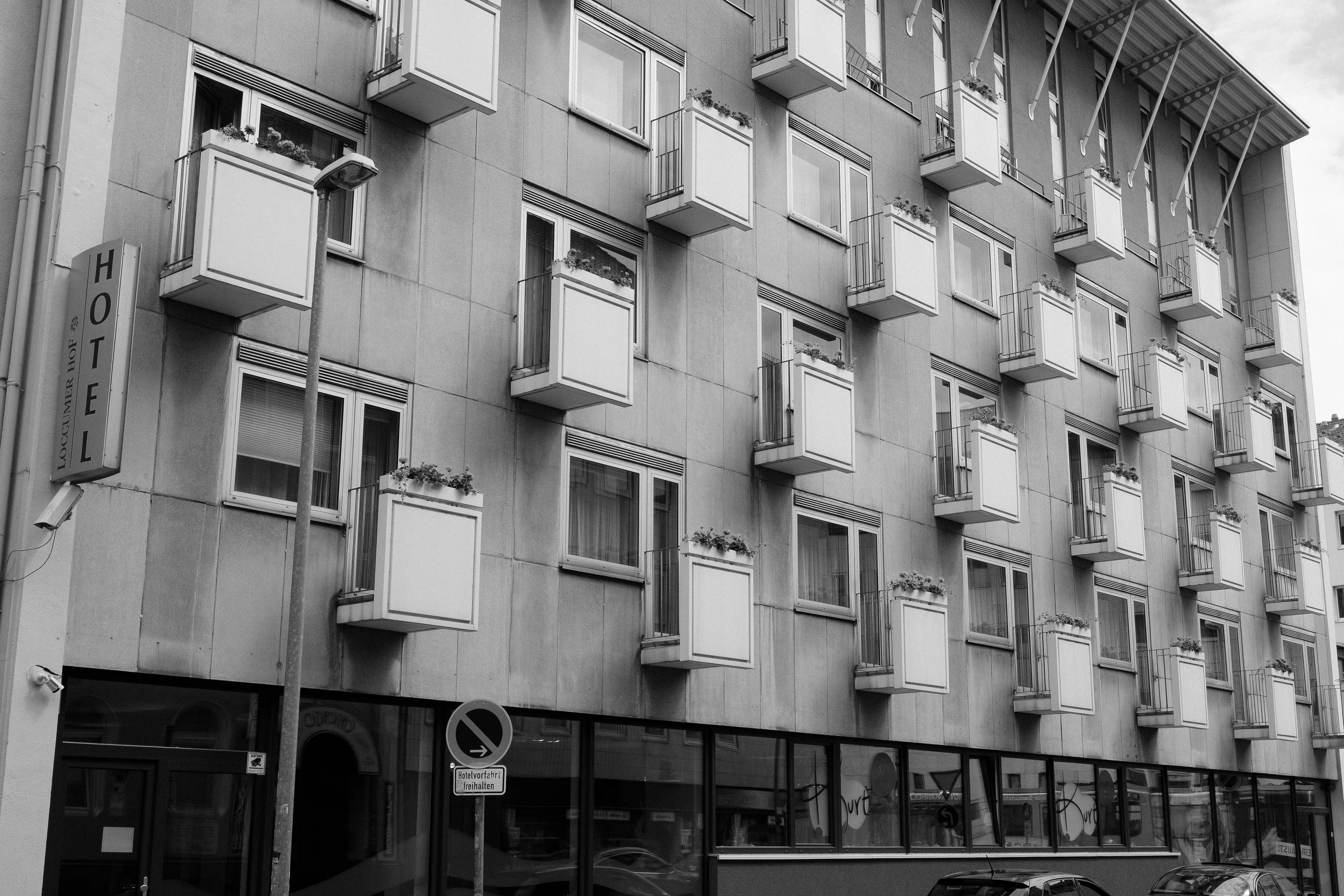 A black and white photo of a hotel facade with multiple small balconies.