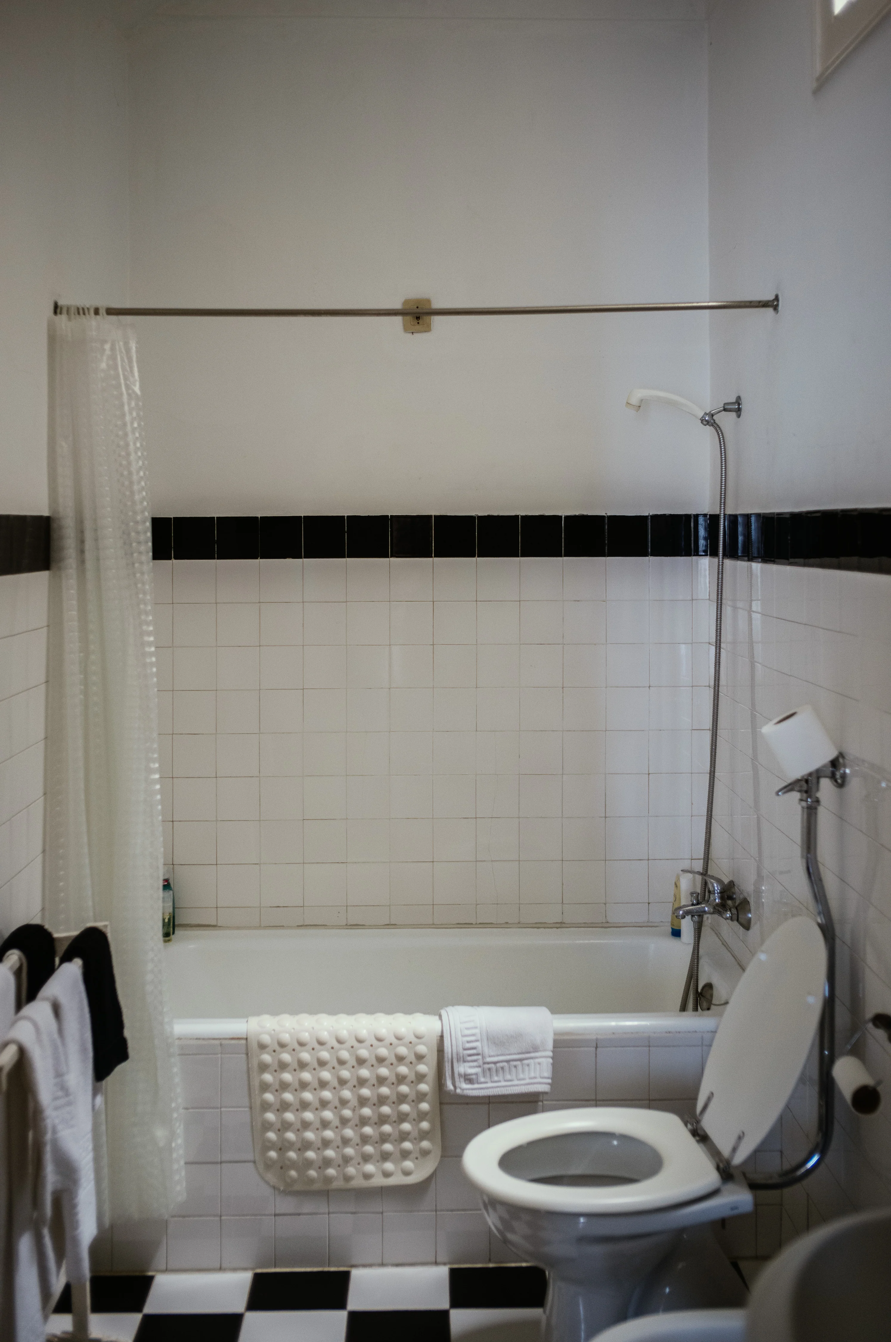 A bathroom with a white tiled bathtub and a toilet in front.