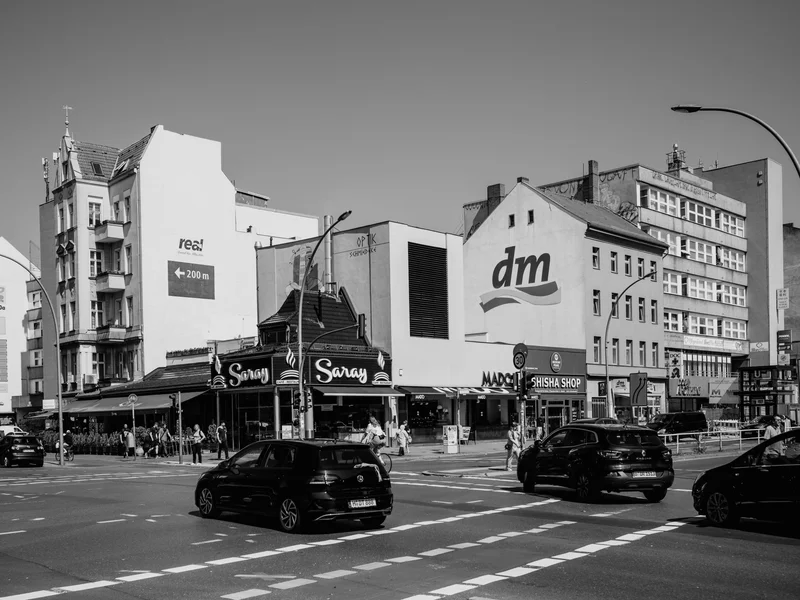Urban street scene with cars and people in front of buildings featuring prominent logos.