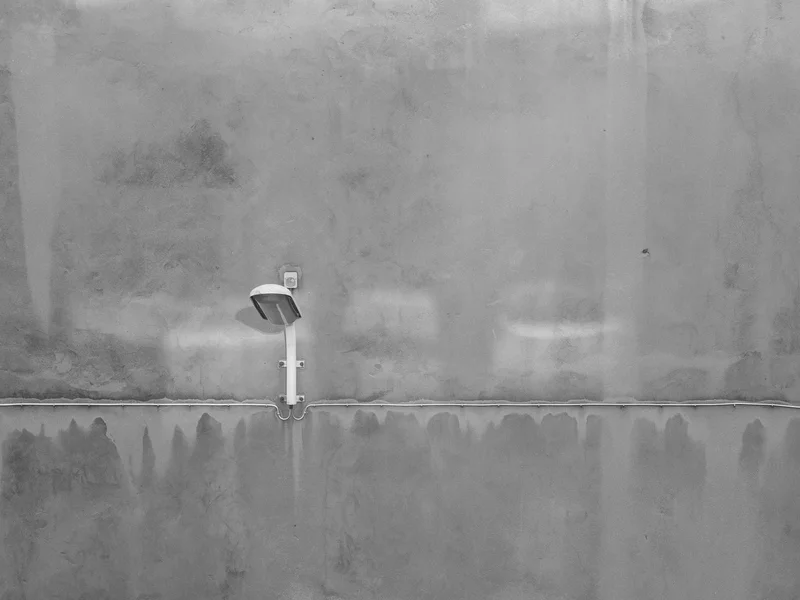 A single wall-mounted light fixture on a textured concrete wall.