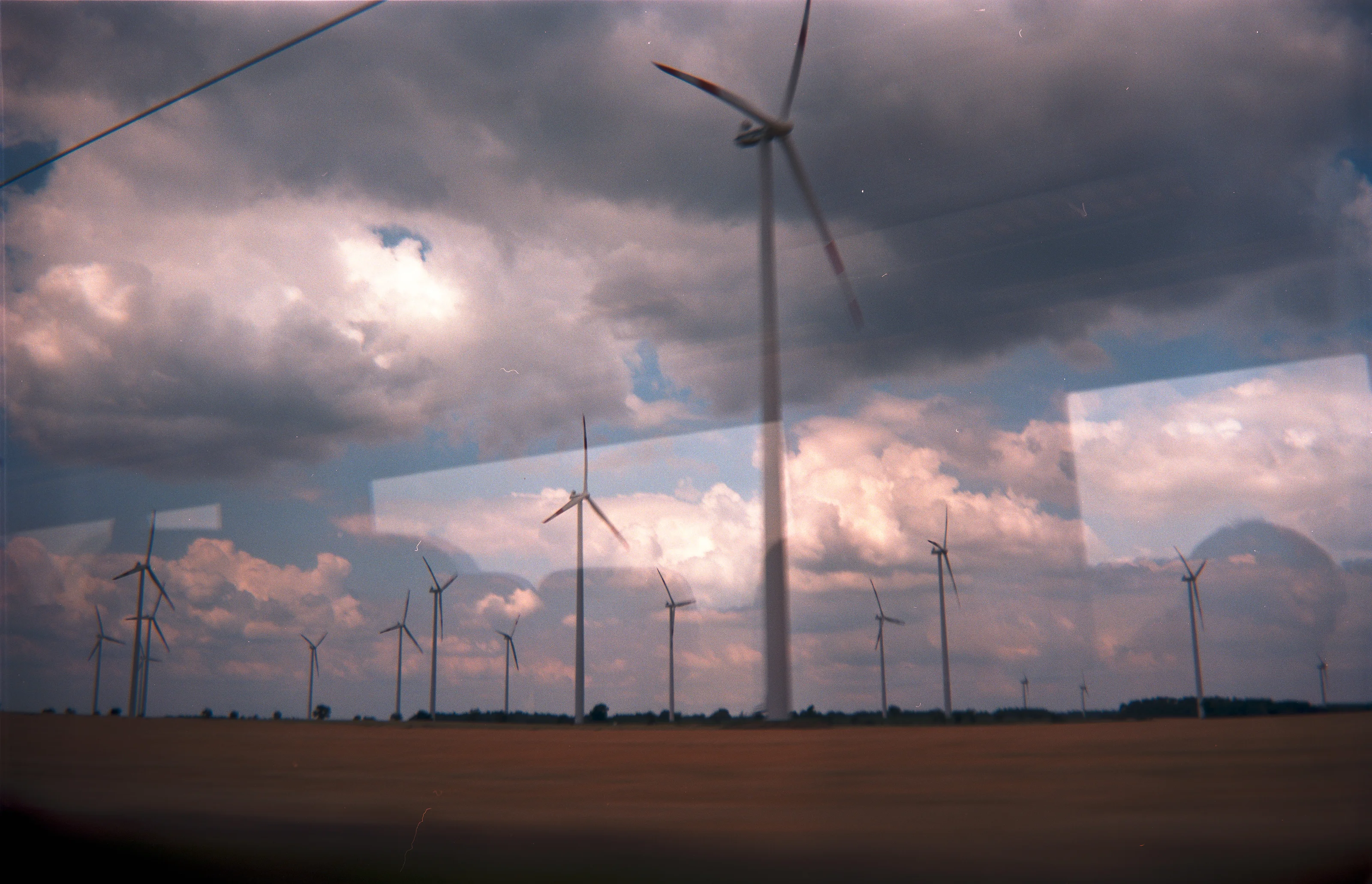Wind turbines in a vast field under a cloudy sky.