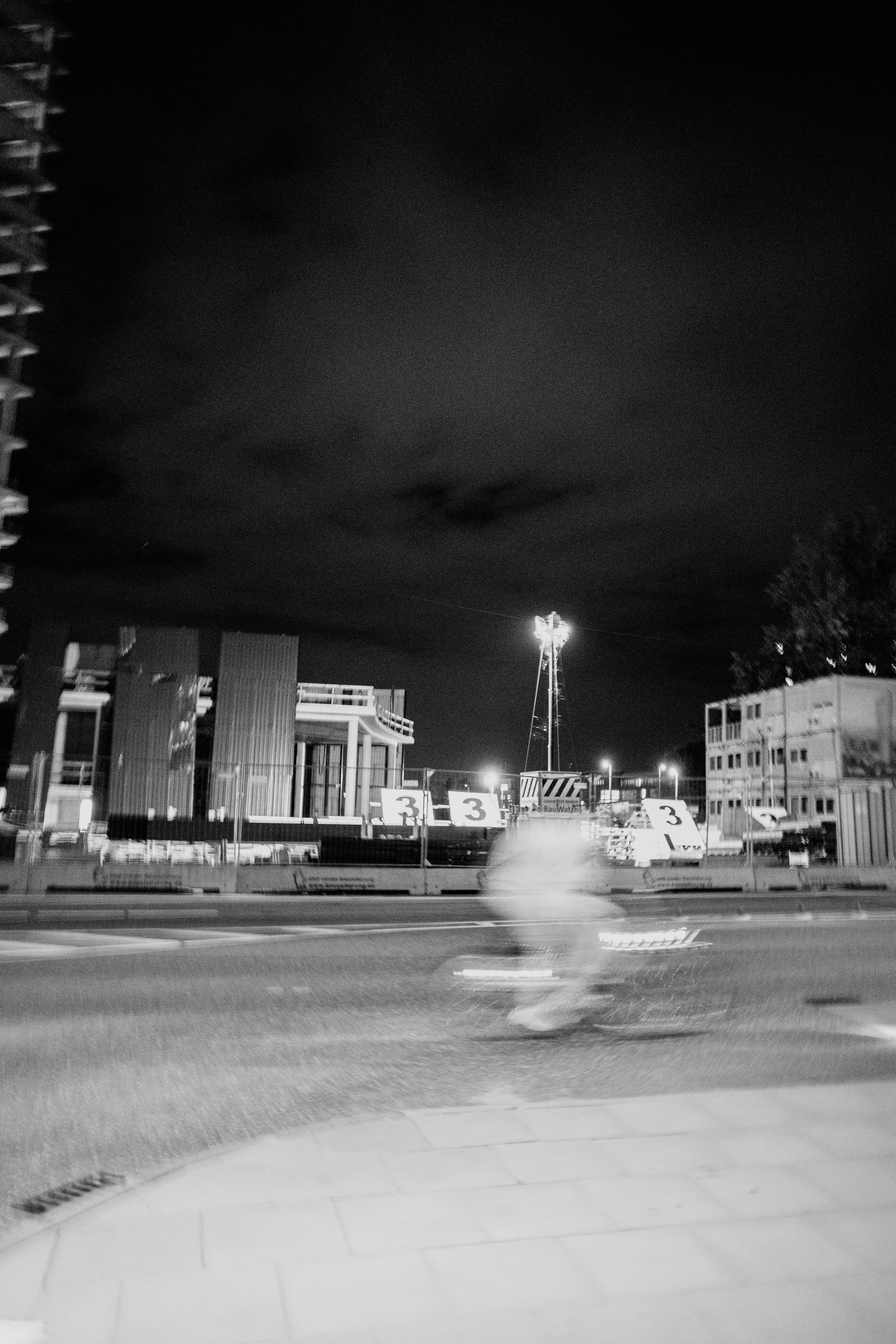 Blurred cyclist passing by a construction site at night.