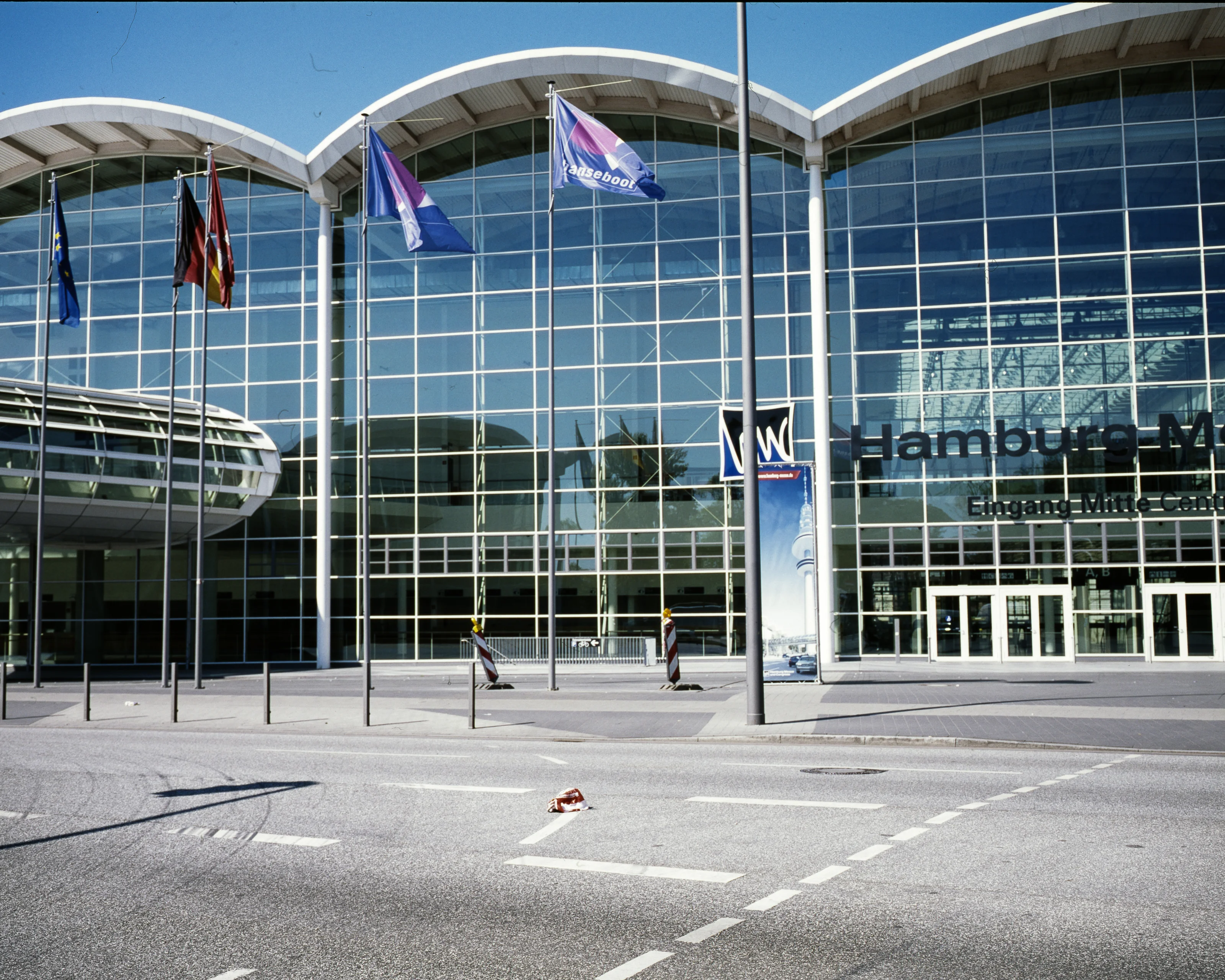 Entrance to Hamburg Messe with flags and large glass facade.