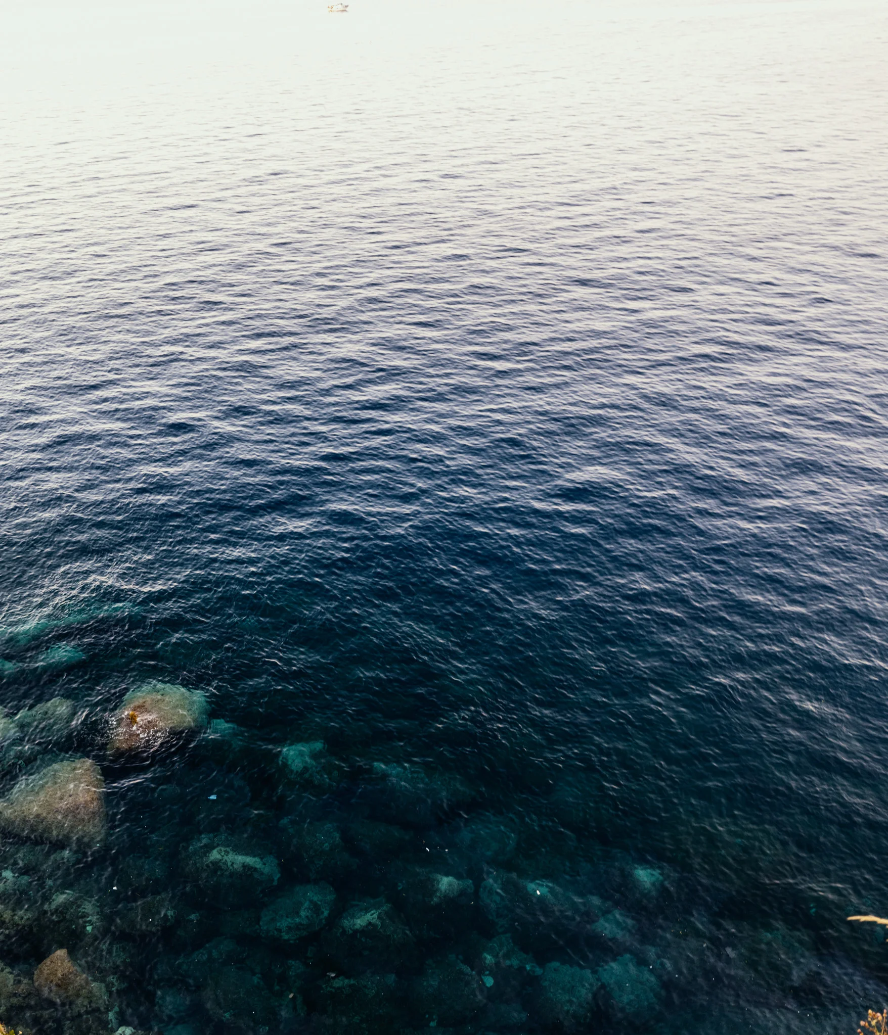 Aerial view of clear blue water with rocks visible beneath the surface.